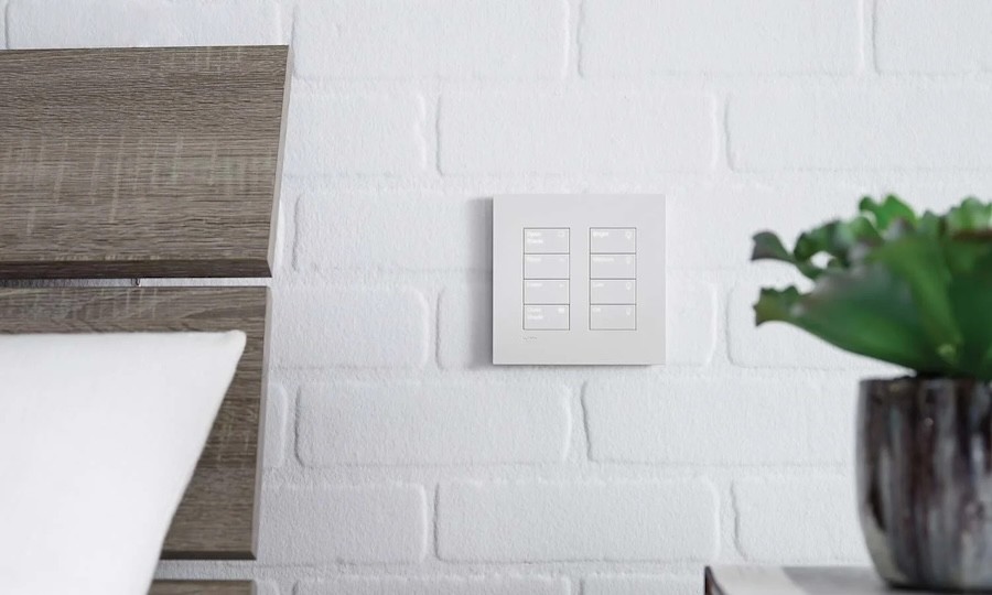 white automated lighting keypad on a white brick wall.