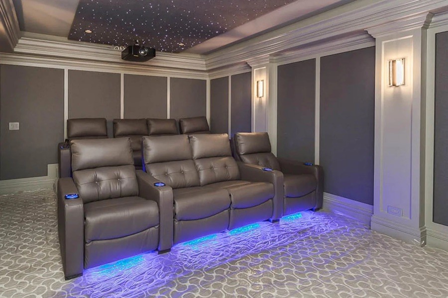 home theater room with blue chairs, a star ceiling, and a projector